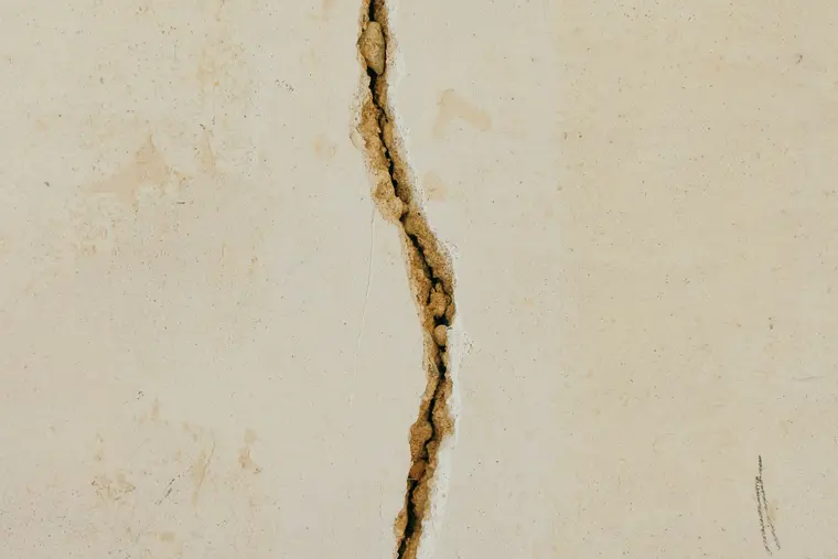 Vertical crack in a concrete wall with brown water staining